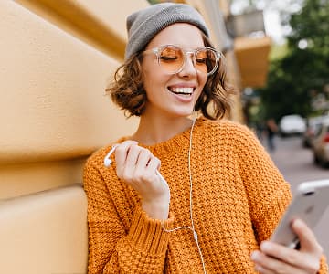 Smiling young woman learning online with smartphone and earphones